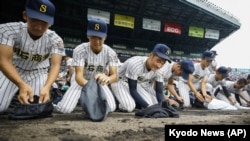 FILE - Akashi Commercial High School baseball players collect dirt of the grounds after being defeated by Riseisha High School during a semifinal game at the National High School Baseball Championship at Koshien Stadium in Nishinomiya on Aug. 20, 2019. (Kyodo News via AP)