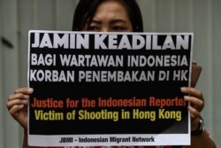 FILE - A woman displays a placard that reads "Justice for the Indonesian reporter," in support of a journalist who was shot in her right eye by police while covering pro-democracy protests Sept. 29, during a rally in Hong Kong, Oct. 11, 2019.
