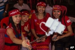 A group of opposition supporters take a selfie as hundreds of people gather outside the opposition party headquarters despite rain in Yangon, Myanmar, Nov. 9, 2015.