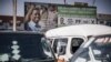 Des voitures sont garées devant des affiches électorales du candidat du Front patriotique au pouvoir Edgar Lungu à la station de taxis du City Market de Lusaka, le 9 août 2021.