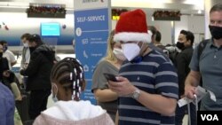 Un pasajero revisa su teléfono celular antes de viajar a Ecuador desde el aeropuerto internacional de Miami. [Foto: Antoni Belchi, VOA]