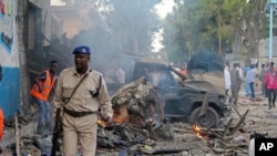 Askari akipita karibu na mabaki ya gari lililolipuka mjini Mogadishu, Somalia Jumamosi, Octoba 28, 2017. 