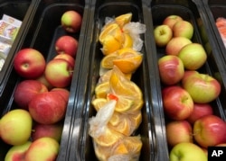 Apples and orange slices rest in trays for student lunch at the Albert D. Lawton Intermediate School, in Essex Junction, Vt., Thursday, June 9, 2022. The pandemic-era federal aid that made school meals available for free to all public school students — regardless of family income levels — is ending, raising fears about the effects in the upcoming school year for families already struggling with rising food and fuel costs. (AP Photo/Lisa Rathke)