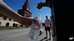 FILE - Tourists fill plastic bottles with water from a public fountain at the Sforzesco Castle, in Milan, Italy, June 25, 2022. (AP Photo/Luca Bruno, File)