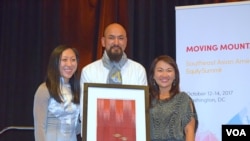 លោក Many Uch (កណ្តាល) ពលរដ្ឋ​អាមេរិកាំង​ដើម​កំណើត​ខ្មែរ​ឡើង​ទទួល​ពានរង្វាន់​បុគ្គល​ផ្លាស់ប្ដូរ​សង្គម​ពី​អ្នក​តំណាង​អង្គការ SEARAC នៅ​សណ្ឋាគារ Renaissance ក្នុង​រដ្ឋធានី វ៉ាស៊ីនតោន កាល​ពី​ថ្ងៃ​ទី​១៣ ខែ​តុលា ឆ្នាំ​២០១៧។ (ហុង ចិន្តា/VOA)