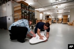 Smithsonian's National Museum of Natural History's Matthew Carrano, curator of Dinosauria, right, and Anna Torres, public affairs specialist, open the protective case containing the of a lower left jaw of a Tyrannosaurus rex skeleton.