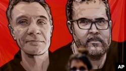 Una empleada de la Fundación Nacional del Indio, FUNAI, junto a una pancarta con la imagen del experto indígena Bruno Pereira (derecha) y del periodista británico Dom Phillips, durante una vigilia en Brasilia, Brasil, el 13 de junio de 2022. 