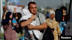 Un hombre carga a un niño mientras miles de palestinos huyen del norte de Gaza caminando hacia el sur, en medio del conflicto entre Israel y el grupo islamista palestino Hamás, el 9 de noviembre de 2023.