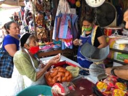 La comerciante Rina Castillo despacha alimentos básicos a los clientes que abarrotaron su mercado.