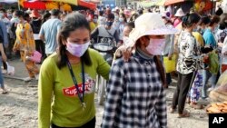 កម្មករ​រោងចក្រ​ពាក់​ម៉ាស់​ការពារ​កុំ​ឲ្យ​ឆ្លង​វីរុស​កូរ៉ូណា ខណៈ​ដែល​ពួកគេ​ដើរចេញ​ពី​រោងចក្រ​ដែល​ពួកគេ​ធ្វើ​ការ ភ្នំពេញ ថ្ងៃ​សុក្រ ទី​២០ ខែមីនា ឆ្នាំ​២០២០។ (AP Photo/Heng Sinith) 