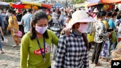 រូបឯកសារ៖ កម្មករ​រោងចក្រ​ពាក់​ម៉ាស់​ការពារ​កុំ​ឲ្យ​ឆ្លង​វីរុស​កូរ៉ូណា ខណៈ​ដែល​ពួកគេ​ដើរចេញ​ពី​រោងចក្រ​ដែល​ពួកគេ​ធ្វើ​ការ ភ្នំពេញ ថ្ងៃ​សុក្រ ទី​២០ ខែមីនា ឆ្នាំ​២០២០។ (AP Photo/Heng Sinith) 