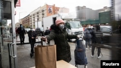 Žena u Njujorku uzima besplatan obrok, 18. april 2020. (Foto: Rojters/Jeenah Moon)