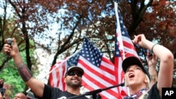 FILE - Joey Gibson, left, leader of Patriot Prayer, participates in the group's rally in Portland, Ore. 