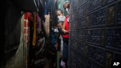 A group of children wearing masks look on as health workers screen people for COVID-19 symptoms at a slum, in Mumbai, India, Wednesday, July 8, 2020. India has overtaken Russia to become the third worst-affected nation by the coronavirus pandemic. …