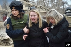 Una psicóloga del servicio de emergencia, a la izquierda, consuela a una mujer en el lugar del ataque aéreo ruso, en Zaporizhzhia, Ucrania, el viernes 22 de marzo de 2024. (Foto AP/Andriy Andriyenko)