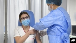 Medicinska sestra iz Rumunije vakciniše se u Bukureštu, 27. decembar 2020. (Foto: AP/Andreea Alexandru)