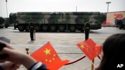 Posmatrači mašu kineskim zastavama dok se vojna vozila sa balističkim projektilima DF-41 kreću tokom parade u Pekingu, Kina, 1. oktobra 2019.