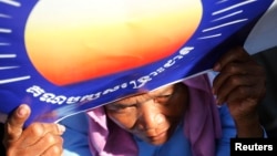 រូបឯកសារ៖ អ្នកគាំទ្រ​គណបក្ស​សង្គ្រោះ​ជាតិ​មួយ​រូប​កាន់​ស្លាក​សញ្ញា​របស់​គណបក្ស​សង្គ្រោះ​ជាតិ​ក្នុង​ពេល​បាតុកម្ម​ទាមទារ​ឲ្យ​មាន​ការបោះឆ្នោត​ដោយ​សេរី​និង​យុត្តិធម៌ ដែល​បាន​ធ្វើ​ឡើង​នៅក្នុង​សួន​ប្រជាធិបតេយ្យ​ក្នុង​ទីក្រុង​ភ្នំពេញ​នៅខែកក្កដា ​ឆ្នាំ២០១៣។