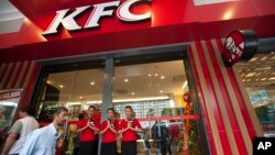 Staff members greet visitors at its grand openning, first branch of Kentucky fried chicken (KFC) restaurant, June 30, 2015, in Yangon, Myanmar.