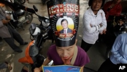 A supporter of the opposition Cambodia National Rescue Party, wears party president Kem Sokha portrait poster read ing"Free" as she stands outside the Supreme Court in Phnom Penh, Cambodia, Tuesday, Oct. 31, 2017. The Supreme Court on Tuesday upheld the lower court's decision to continue detaining opposition leader Kem Sokha, who has been charged with treason, the latest in a series of moves to gain an advantage ahead of next year's general election. (AP Photo/Heng Sinith)