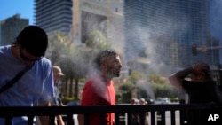 ARCHIVO - La gente se refresca con atomizadores a lo largo del Strip de Las Vegas, el 7 de julio de 2024, en Las Vegas.