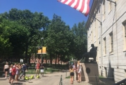 资料照片：游人与哈佛大学的约翰·哈佛铜像合影。