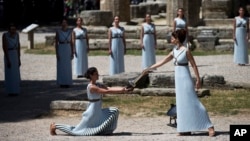High Priestess Katerina Lehou, (r) lights a pot with a backup flame for the Rio Olympics in front of the ancient temple of Hera, during the dress rehearsal for the lighting of the Rio Olympics flame, in Ancient Olympia, Greece, April 20, 2016.