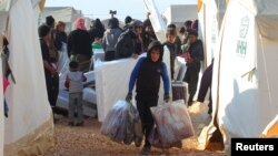 A boy, an evacuee from a rebel-held area of Aleppo, carries blankets he received as as part of an aid kit, in al-Kamouneh camp, Idlib province, Syria Dec. 29, 2016.