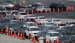 Lines of cars wait at a drive-through coronavirus testing site, Sunday, July 5, 2020, outside Hard Rock Stadium in Miami Gardens, Fla.