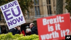 Pro and anti Brexit protesters hold placards as they vie for media attention near Parliament in London, Nov. 16, 2018. Britain's Prime Minister May still faces the threat of a no-confidence vote, after several Conservative Party lawmakers said they had wr