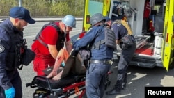 Policajci i bolničari zbrinjavaju čoveka ranjenog u ruskom vazdušnom udaru u Harkovu, Ukraina, 9. aprila 2024.