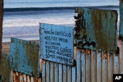 A sign that reads in Spanish "No obstacle can stop us from our dreams. We are Mexicans. We are unstoppable," hangs on border structure from the Mexican side where the border meets the Pacific Ocean, Nov. 16, 2018.