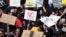 FILE - Women hold placards as they protest against gender-based violence, outside the Johannesburg Stock Exchange in Sandton, Johannesburg, South Africa, Sept. 13, 2019. 