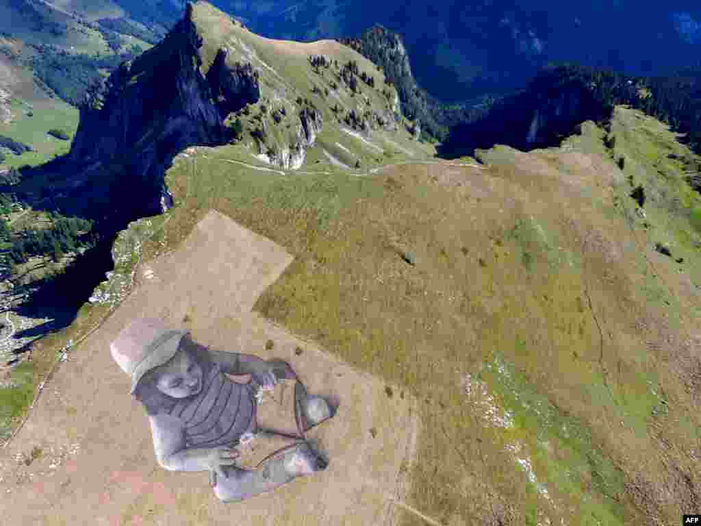 This handout picture received from French artist Guillaume Legros shows a general view of a land art painting by Legros (also known as Sapye) measuring some 6,000 square meters and entitled "A story of the future" painted on a hillside in Rochers de Naye in Switzerland.