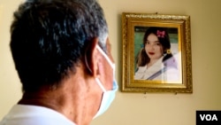 លោក លី គឿង ឪពុករបស់យុវតីវ័យ ២០ឆ្នាំ ដែលបានបាត់បង់ជីវិតក្នុងគ្រោះថ្នាក់ កំពុងឈរមើលរូបថតកូនស្រី នៅផ្ទះរបស់លោក ក្នុងខេត្តកំពង់ឆ្នាំង កាលពីថ្ងៃទី២៤ ខែតុលា ឆ្នាំ២០២១។ (កាន់ វិច្ឆិកា/វីអូអេ) 