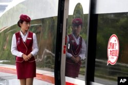 An attendee waits for passengers to board the Fuxing, China's latest high speed train with a sticker reads "Incredible, my country" parked at Hongqiao Railway Station in Shanghai, China, Oct. 16, 2017.
