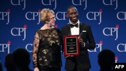 លោកស្រី Sandra Mims Rowe (ឆ្វេង)​ និង​លោក Maxence Melo Mubyazi ថត​រូប​នៅ​លើ​ឆាក​ក្នុង​ពីធី​ប្រគល់​​​ពាន​រង្វាន់​សេរីភាព​សារព័ត៌មាន​អន្តរជាតិ​លើក​ទី​២៩​​ កាល​ពី​ថ្ងៃ​ទី​២១ ខែ​វិច្ឆិកា​ ឆ្នាំ​២០១៩ នៅ​ទី​ក្រុង​ញូវយ៉ក សហរដ្ឋ​អាមេរិក។