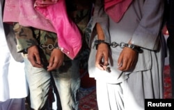 FILE - Two men in handcuffs, whom police said belonged to the Tehreek-e-Taliban Pakistan group, are shown during a news conference at the Crime Investigation Department after their arrest, in Karachi, January 2013.