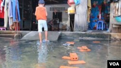 រូបឯកសារ៖ ក្មេងស្រី​ម្នាក់​ឈរ​ក្នុង​ទឹក​ដែល​លិច​នៅ​មុខ​ផ្ទះ​របស់​លោក ឃឹន សុវាត ដែល​ស្ថិត​នៅ​ក្នុង​តំបន់​បឹងកក់ ក្នុង​ទីក្រុង​ភ្នំពេញ​នៃ​ប្រទេស​កម្ពុជា នៅ​ថ្ងៃ​ទី​១៣ ខែ​វិច្ឆិកា ឆ្នាំ​២០១៤។ (VOA)