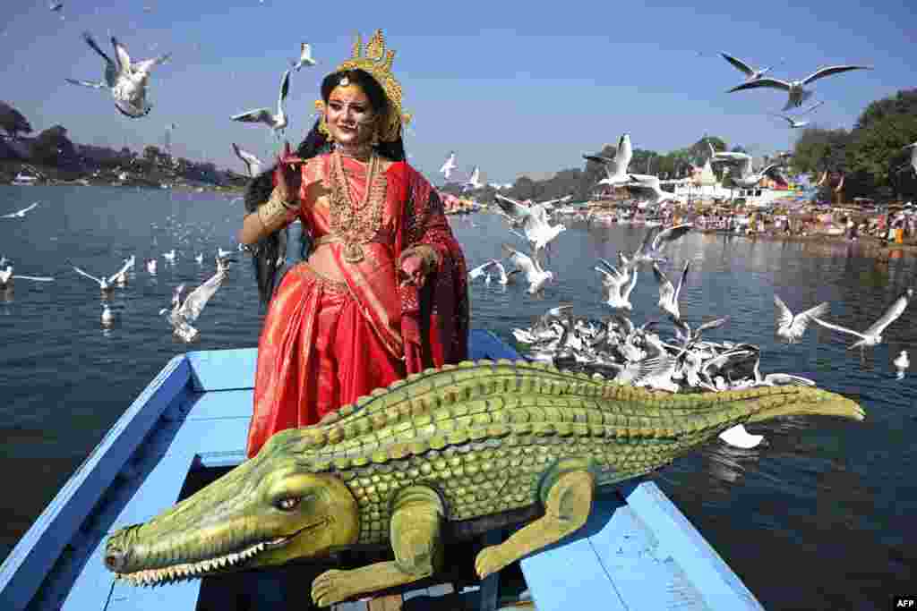 An artist dressed as Goddess Narmada, the river deity named after the Narmada River, accompanied by her vahana (deity's carrier), the crocodile, poses for pictures ahead of Narmada Jayanti celebrations in Jabalpur.