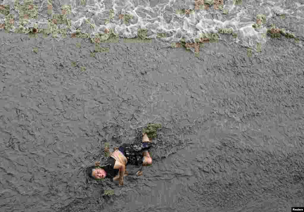 A man who has fallen off a bridge lies in the water as waves approach, on the banks of Qiantang River in Hangzhou, Zhejiang province, China, July 25, 2016.