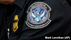 Таможенник с нашивкой Агентства таможенной и пограничной охраны США, в Международном аэропорту имени Джона Ф. Кеннеди в Нью-Йорке, 27 октября 2017 года,