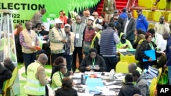 Mwenyekiti wa IEBC, Wafula Chebukati, aliye kati na shati jekundu, makamishina wa IEBC katika kituo cha taifa cha kujumuisha kura cha Bomas nchini Kenya, Nairobi, Kenya, Sunday, Aug.1 4, 2022. (AP Photo/Sayyid Abdul Azim)