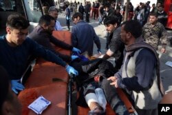 An injured man is moved to a stretcher outside a hospital following a suicide attack in Kabul, Afghanistan, Jan. 27, 2018.