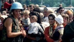 Žene i deca, uz pripadnika holandskog bataljona UN, čekaju na transportovanje iz Potočara; 12. jul 1995.