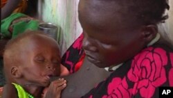 In this photo taken from Video provided by Associated Press on Tuesday, May 13, 2014, a malnourished child is fed by her mother, in a Medecins Sans Frontiers (Doctors Without Borders) hospital, in Leer, South Sudan. Bodies stuffed in wells. Houses burn