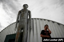 FILE - In this July 22, 2019 file photo, Linda Looney wipes her face outside of the Alien Research Center, a gift shop on the Extraterrestrial Highway, in Crystal Springs, Nevada.