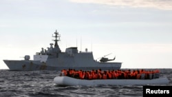 Des migrants africains à bord d'un radeau surchargé à la dérive, près d'un navire de la Marine italienne, sont secourus par l'ONG espagnole Proactiva Open Arms en mer méditerranéenne, le 2 janvier 2017.