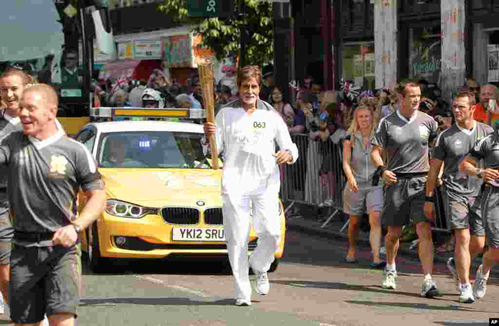 Bollywood actor Amitabh Bachchan carries the Olympic flame on the torch relay leg between The City of London and the borough of Southwark in London, July 25, 2012. (Photo provided by LOCOG)