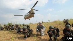 Philippine soldiers and a US army soldier from 2nd Stryker Brigade Combat of the 5th Infantry Division take their positions after disembarking from a C-47 Chinook helicopter during an air assault exercise inside the military training camp of Fort Magsaysay in Nueva Ecija province north of Manila, April 20, 2015.